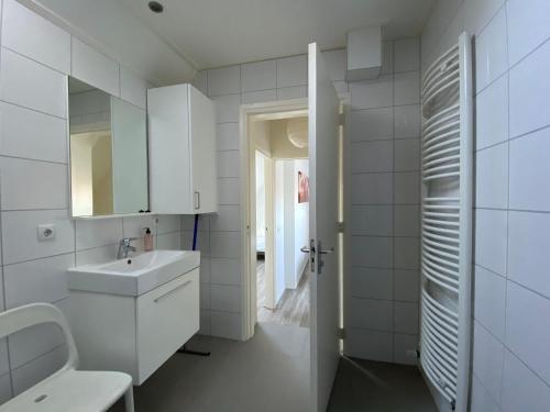 a white bathroom with a sink and a mirror at Vakantiewoning Scheldestraat 23 Zoutelande, dicht bij Domburg in Zoutelande