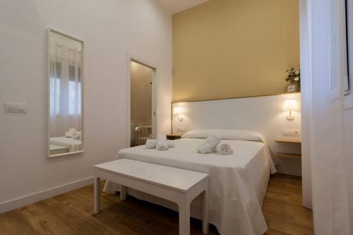een witte slaapkamer met een bed en een tafel bij Apartamento Las 3 Gaviotas in Cádiz