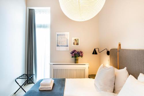 a bedroom with a white bed and a large chandelier at The Beach apartments by Daniel&Jacob's in Copenhagen