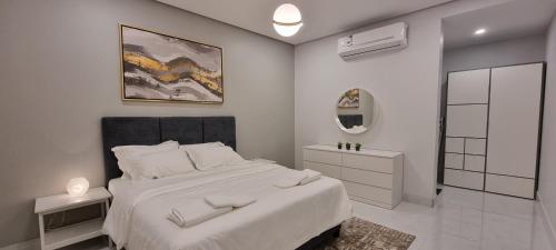 a white bedroom with a large bed and a mirror at مساكن كيو in Dammam