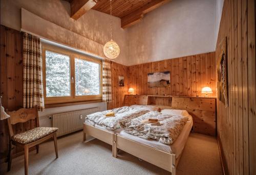 a bedroom with a bed and a chair in it at Casa Dschember, Wohnung 10, 1-5 Personen in Arosa