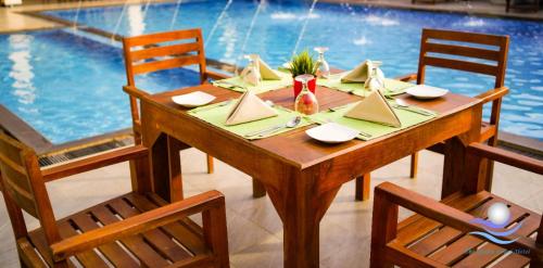 a wooden table with two chairs and a swimming pool at The Ocean Pearl Hotel Negombo in Negombo