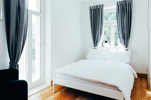 a white bed in a room with windows at Hostel Multitude in Leipzig