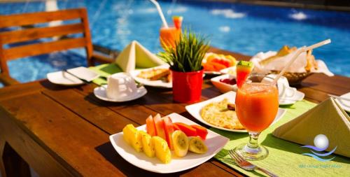 a wooden table with plates of food and a drink at The Ocean Pearl Hotel Negombo in Negombo