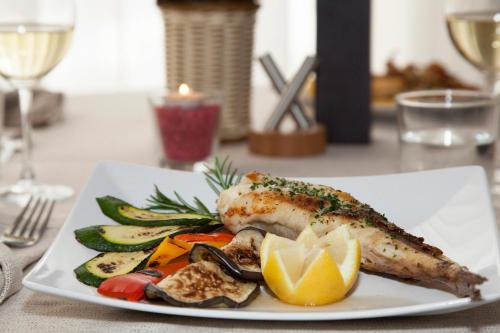 a plate of food with fish and vegetables on a table at Hotel Helvetia in Lido di Jesolo