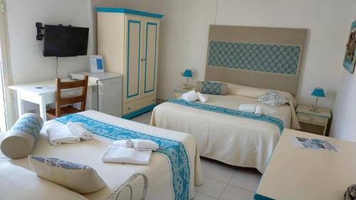 a room with two beds and a desk and a television at Hotel Canne al Vento in Santa Teresa Gallura