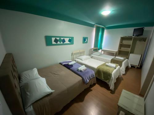 a bedroom with two beds and a television in it at Hotel Domo in Prudentópolis