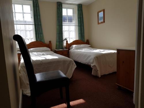 een hotelkamer met 2 bedden en een stoel bij The Westgate in Bury Saint Edmunds