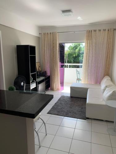 a living room with a white couch and a tv at Localização estratégica em Lauro Próximo ao Aeroporto e Shopping in Lauro de Freitas