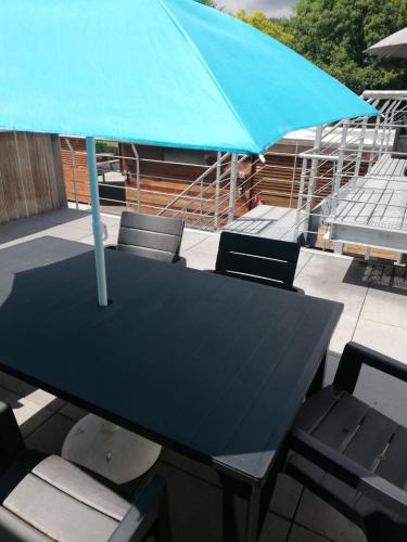 a black table and chairs with a blue umbrella at NUVOLA Summer Spring in Zottegem