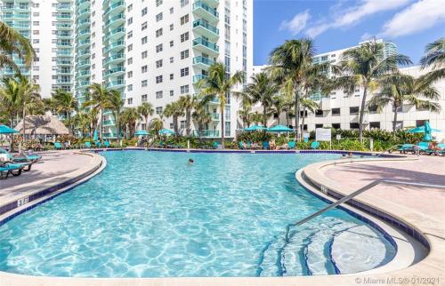 uma piscina num resort com palmeiras e edifícios em Dream Vacation Apartment Right On The Beach em Hollywood