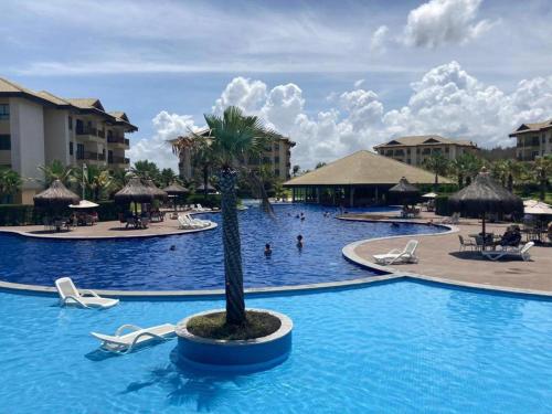 a pool at a resort with chairs and a palm tree at Cumbuco - VGSun Apartment 402 in Cumbuco
