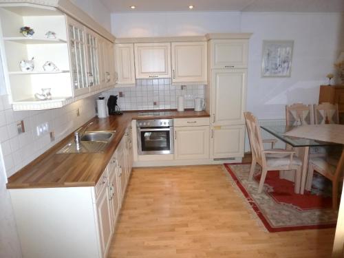 a kitchen with white cabinets and a sink and a table at Geary Ferienwohnung in Klotten