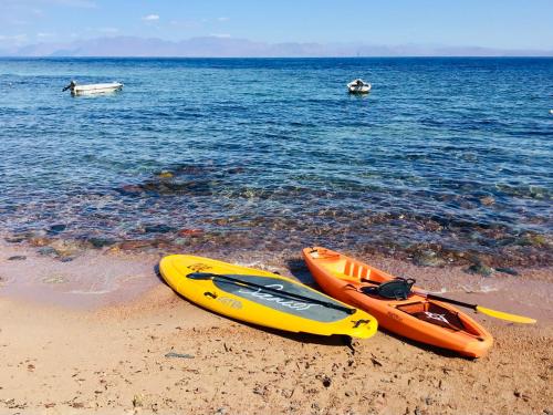 two kayaks sitting on a beach near the water at Villa Kon Tiki with private beach in Dahab