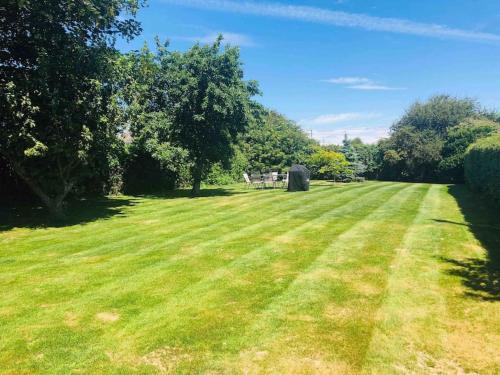 a large grassy field with trees in the background at The Attic Suite Selsey in Selsey