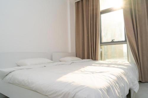 a white bed in a room with a window at Atlantis International Hotel Apartments in Kuwait