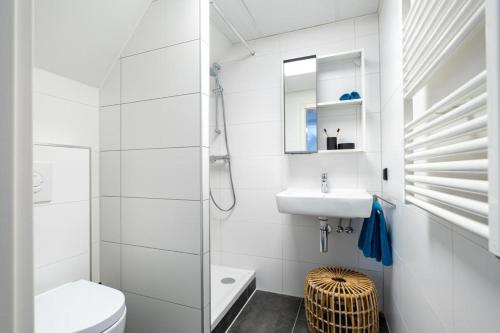 a white bathroom with a toilet and a sink at Hotel La Source Epen in Epen