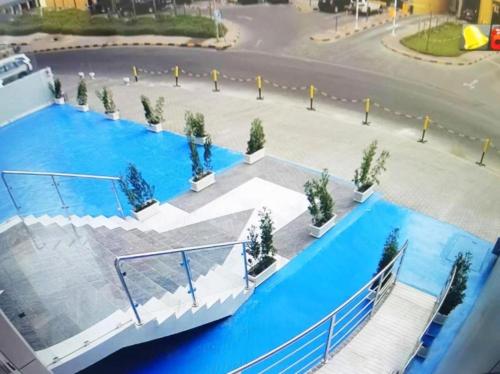 a large swimming pool with trees on a street at Atlantis International Hotel Apartments in Kuwait