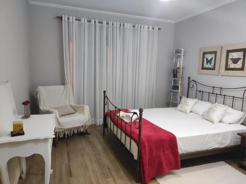 a bedroom with a bed with a red blanket and a chair at Refúgio da família - serra & lago in Guapimirim