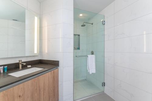 Global Luxury Suites Miami Worldcenter في ميامي: حمام مع دش ومغسلة ودش كشك زجاجي