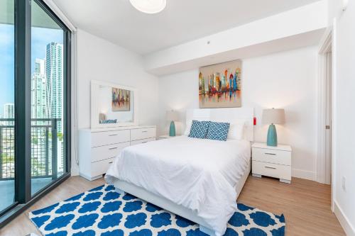 a white bedroom with a bed and a large window at Global Luxury Suites Miami Worldcenter in Miami