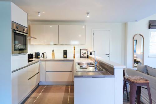 a white kitchen with a sink and a couch at Apartments in the countryside near Brussels in Lasne