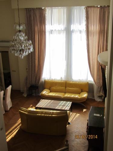 - un salon avec un canapé jaune en face des fenêtres dans l'établissement Duplex à la Villa Canteraine, à Cannes