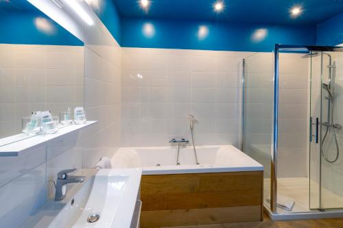 a bathroom with a tub and a glass shower at Le Gîte de la Plage in Étretat