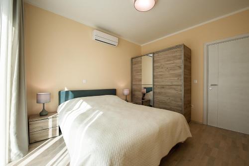 a bedroom with a large white bed and a mirror at Adria Lux Apartments Sveti Stefan in Budva