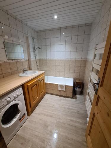 a bathroom with a tub and a sink and a washing machine at Apartment Residence Les Alpages in La Giettaz
