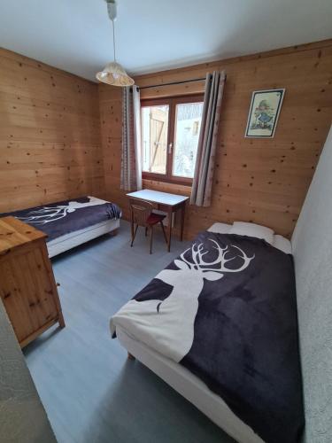 a bedroom with two beds and a table in it at Apartment Residence Les Alpages in La Giettaz