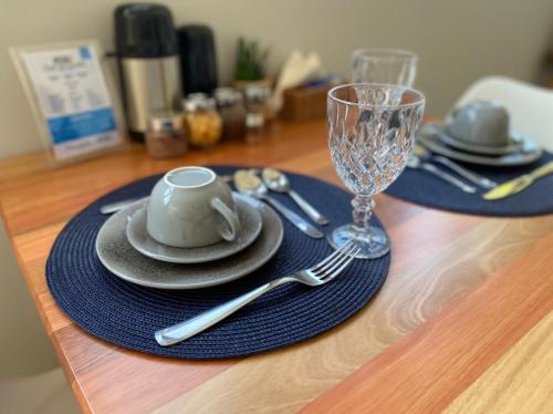 a table with a cup and plates and a wine glass at Pousada da Mana in Fernando de Noronha