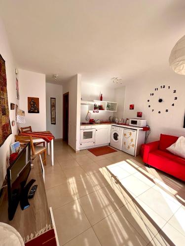 a living room with a red couch and a kitchen at La Casita Sun Beach in Caleta De Fuste
