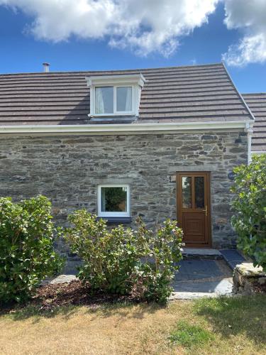 a stone house with a window and a door at Canllefaes Cottages in Cardigan