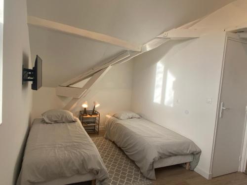 two beds in a room with a attic at Studio dans les écuries du chateau in Bonnelles