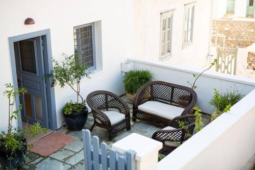 a balcony with wicker chairs and a blue door at Nefeli Villa in Hydra
