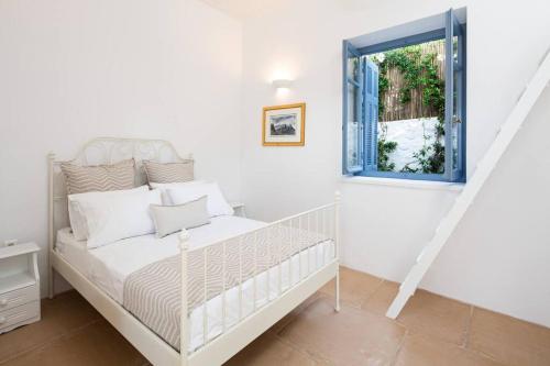 a white bedroom with a bed and a window at Nefeli Villa in Hydra
