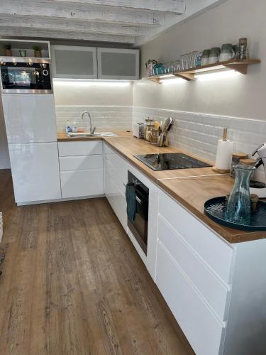 une cuisine avec des armoires blanches et un plancher en bois dans l'établissement Maisonnette à 300 m du lac de Biscarrosse, à Biscarrosse