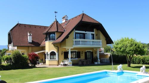 a house with a swimming pool in front of it at Appartements Panorama Schlössl in Velden am Wörthersee