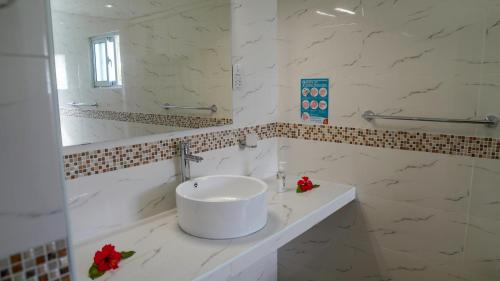 a white bathroom with a sink and a mirror at Villa Antonia in La Digue