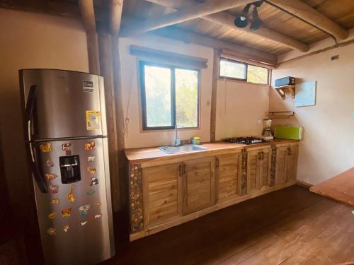 La cuisine est équipée d'un réfrigérateur en acier inoxydable et de placards en bois. dans l'établissement Ankua Eco Hotel, à Usiacurí
