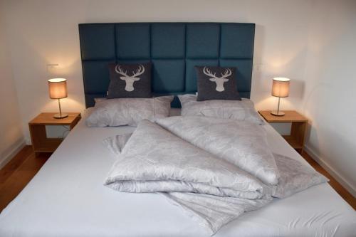a bedroom with two beds with white sheets and two lamps at Ferienhaus Nockalmbahn in Bad Kleinkirchheim