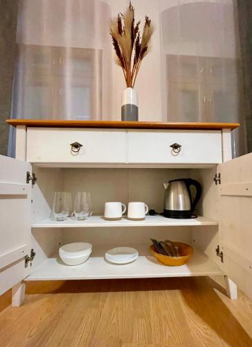 a white hutch with plates and bowls in it at Dorfel in Košice