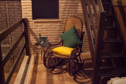 a rocking chair with a pillow on a balcony at SEÑORÍO de ORGAZ "Con Patio TOLEDANO" in Toledo