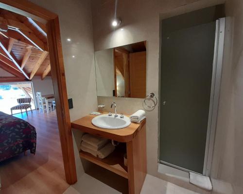 a bathroom with a sink and a mirror and a bed at La Estancia Cabañas in Villa La Angostura