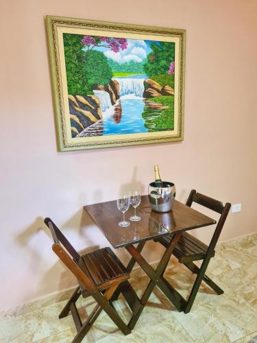 a table and chairs with a painting of a waterfall at Pássaros do Cerrado Suítes in Alto Paraíso de Goiás