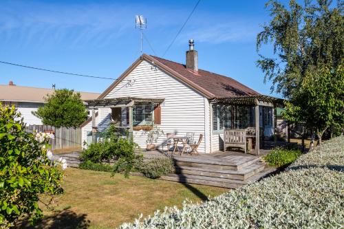 une maison blanche avec une terrasse en bois dans la cour dans l'établissement Strasbourge Cottage, à Martinborough