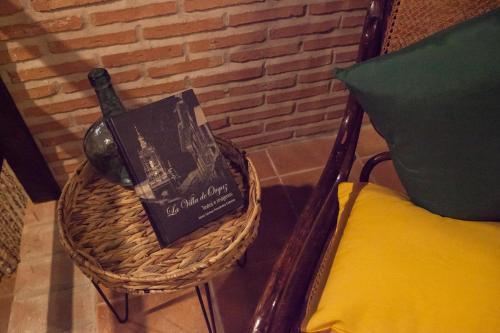 eine Flasche Wein und ein Buch auf einem Korb neben einem Stuhl in der Unterkunft SEÑORÍO de ORGAZ "Con Patio TOLEDANO" in Toledo