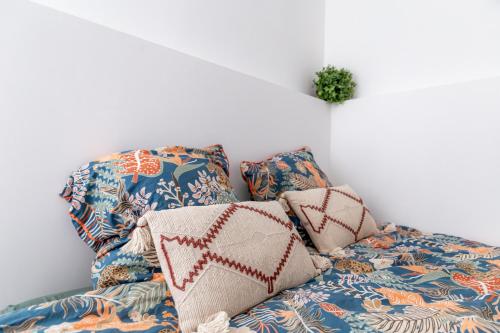 ein Bett mit Kissen darauf in einem Zimmer in der Unterkunft L'escale - Ma Cabotte in Bourg-en-Bresse