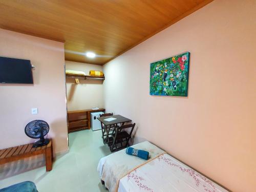 a bedroom with a bed and a painting on the wall at Pássaros do Cerrado Suítes in Alto Paraíso de Goiás